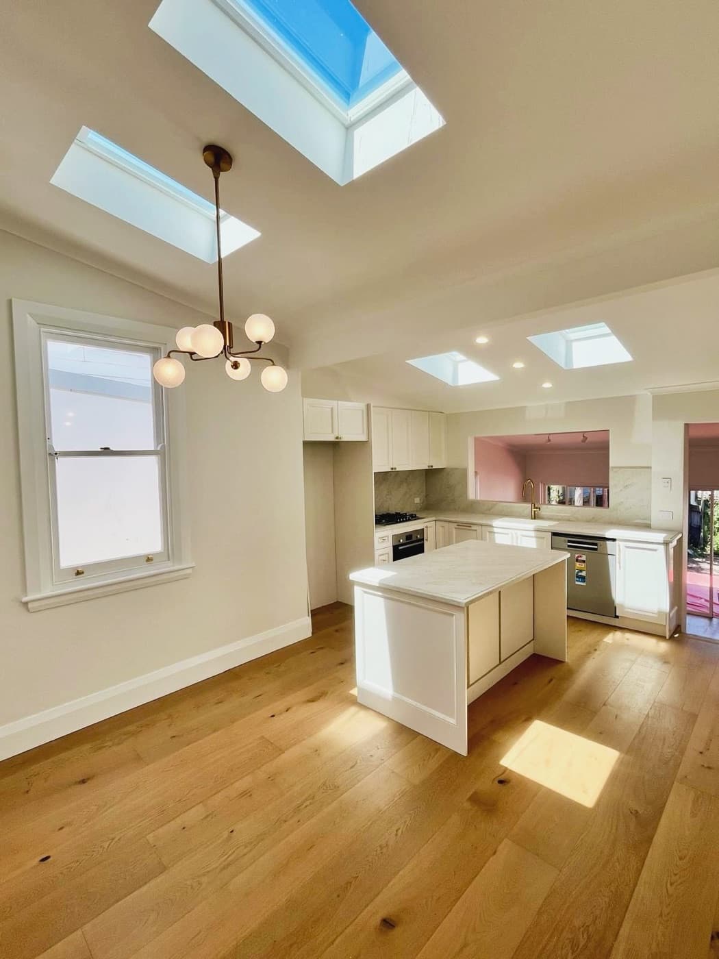 A renovated kitchen with a globe chandelier and skylights